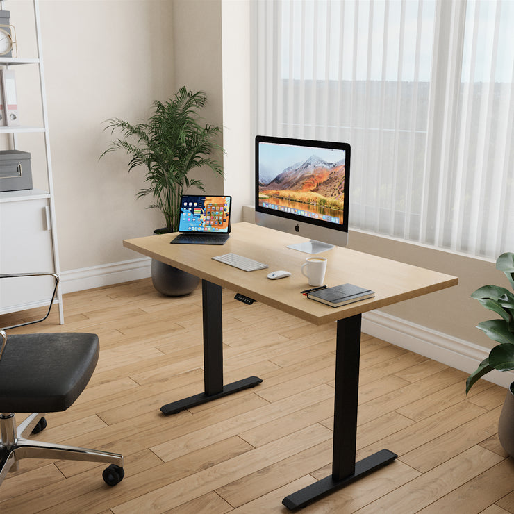 A well-lit home office showcasing a maple standing desk with black legs. This desk, made in Canada, brightens up the workspace while promoting better posture and ergonomics.