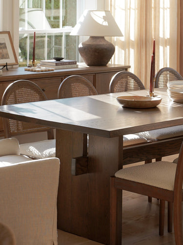 Dining room with a large table and chairs, large windows, and decorative elements.