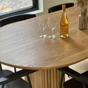 Detailed close-up showcasing the fine wood grain of the Canadian-made OVALI oval dining table, set in a chic dining room.