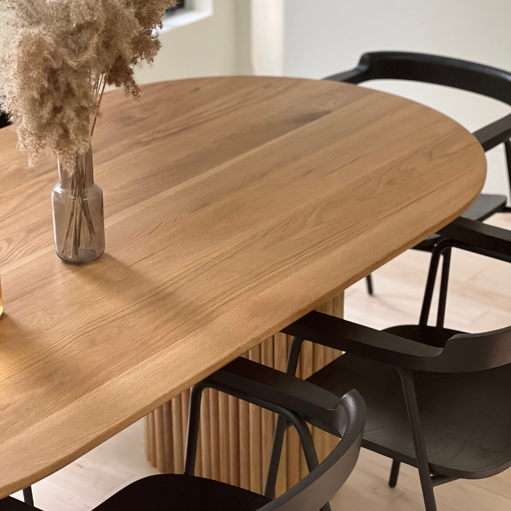 A high-end wooden dining table in a beautiful dining room set up with a beautiful vase..
