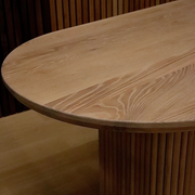 Close-up view in the showroom spotlighting the flawless finish and rich wood grain of the OVALI oval dining table.